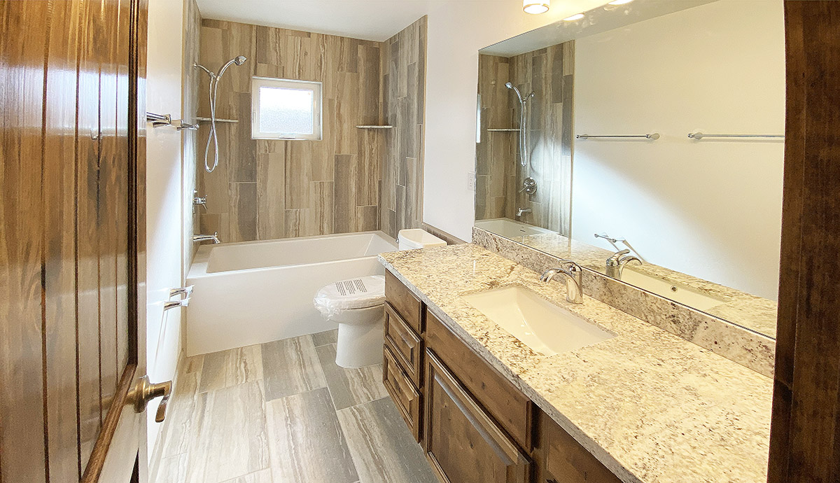 Remodeled guest bathroom with new tile, granite countertops, rustic cabinets and new lighting