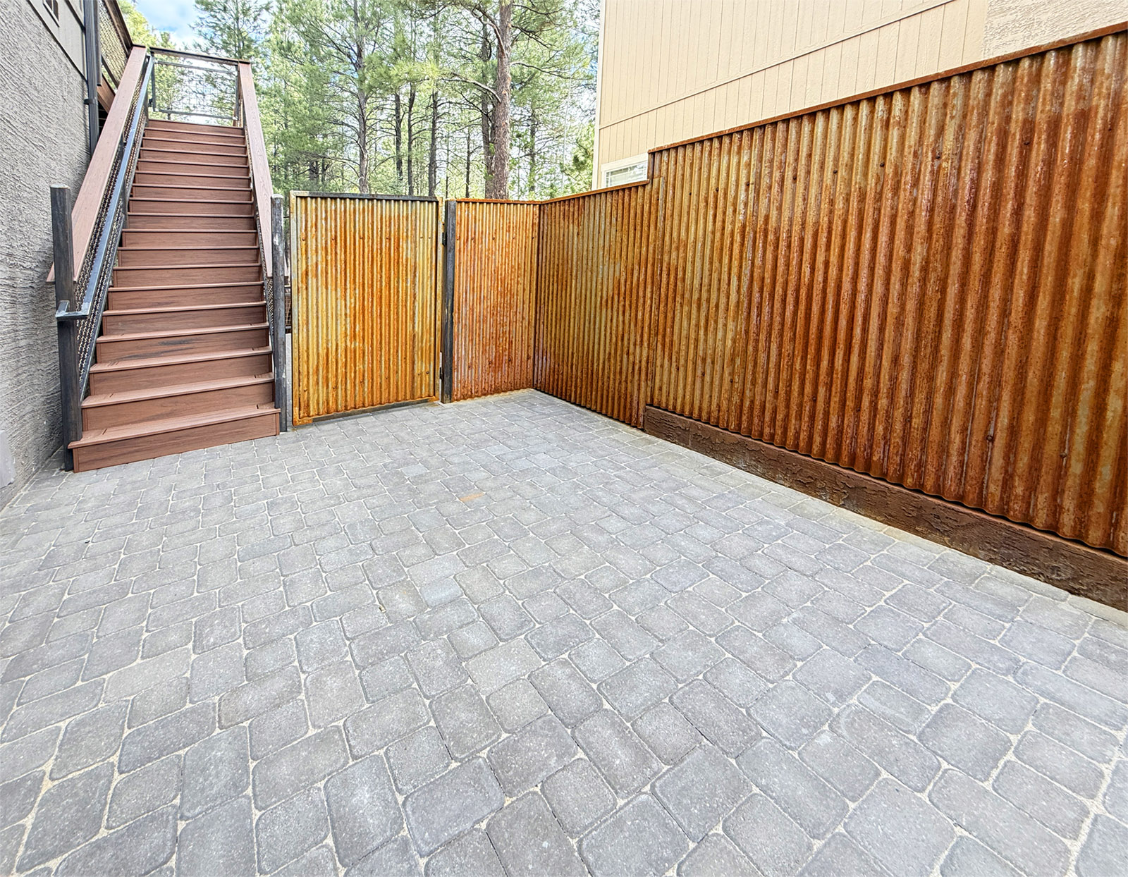 Custom Courtyard Highwood Construction designed this custom courtyard that includes new pavers and a rusted metal fence. Also pictured is a Trex composite staircase. Location is Ponderosa Trails neighborhood in Flagstaff Arizona.