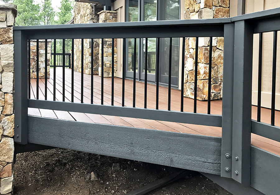 black round aluminum balusters in a redwood railing that is stained black
