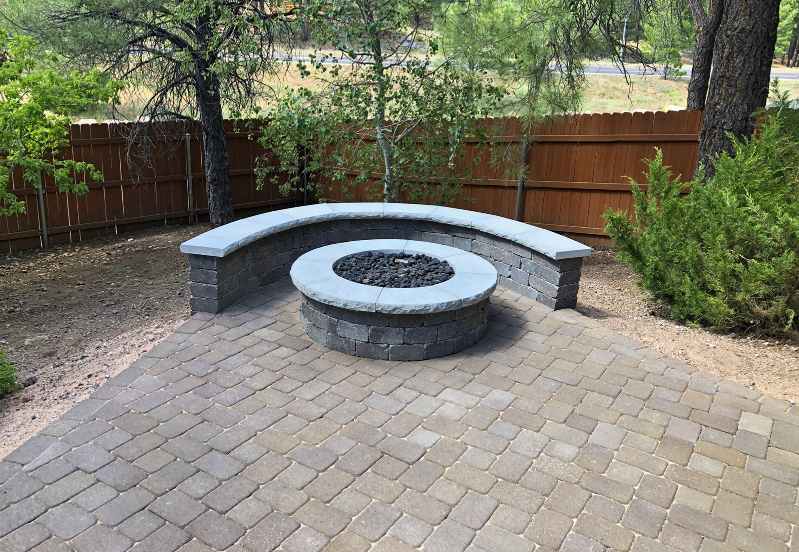 Paver patio with a firepit in the corner surrounded by seating pavers.