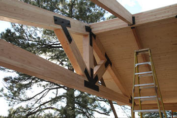 Custom carpentry of lodge style beams with custom steel brackets over deck in Flagstaff Arizona
