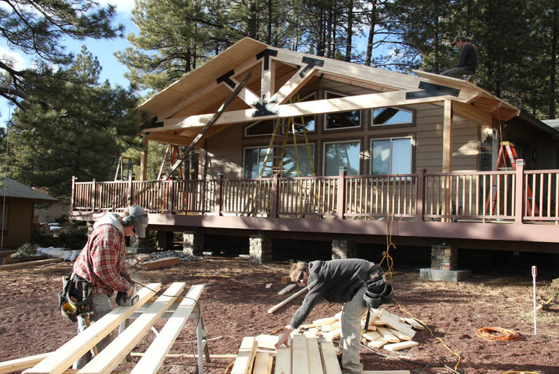 Carpenters at work constructing a patio cover with lodge style beams and custom brackets in Munds Park Arizona